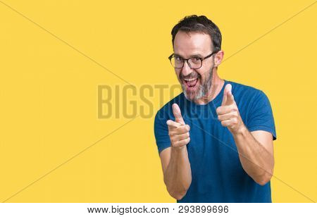 Handsome middle age hoary senior man wearin glasses over isolated background pointing fingers to camera with happy and funny face. Good energy and vibes.