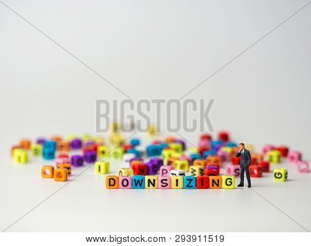 Miniature Figure Businessman In Dark Blue Suit Standing Backside Of Colorful Of Downsizing Alphabet 