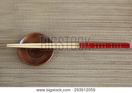 Two Wooden Chopsticks, Small Brown Bowl Served On Wooden Background. Asian Traditional Bamboo Applia
