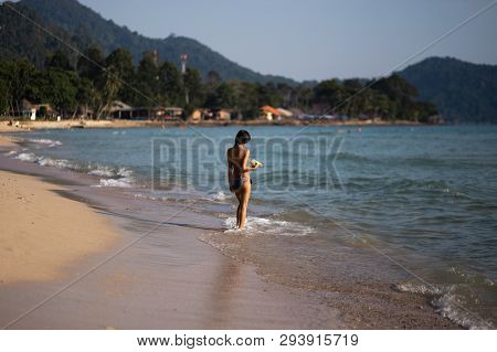 Ko Chang, Thailand - April 9, 2018: Genuine Asian Thay Girl Walking Along The Sea On A Beach With Am