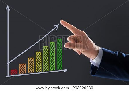 Businessman Pointing At Efficiency Graph On Virtual Screen Against Dark Background, Closeup