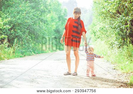 The Child Learns To Walk In The Park Barefoot On The Grass