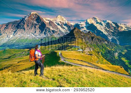 Famous Mannlichen Tourist Resort And Cable Car Station. Backpacker Hiker Woman Enjoying The View Wit
