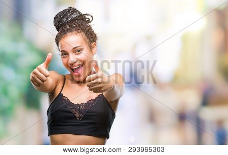 Young braided hair african american with pigmentation blemish birth mark over isolated background approving doing positive gesture with hand, thumbs up smiling and happy for success. Looking