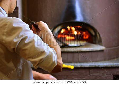 Pizza Maker In Pizzeria Makes Pizza In Wood-fired Oven
