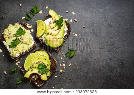 Sandwiches With Avocado And Cream Cheese With Grain Bread And Seeds. Black Slate Background, Top Vie