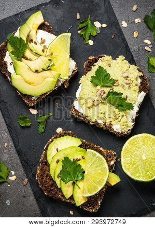 Sandwiches With Avocado And Cream Cheese With Grain Bread And Seeds. Black Slate Background, Top Vie