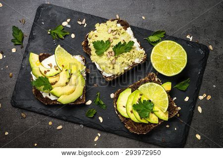 Sandwiches With Avocado And Cream Cheese With Grain Bread And Seeds. Black Slate Background, Top Vie