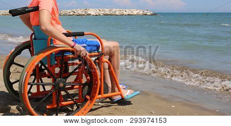 Young Boy On The Wheelchair On The Beach By The Sea In Summer