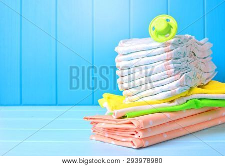 Baby Accessories Background. Pile Of Diapers, Napkins And Dummy.