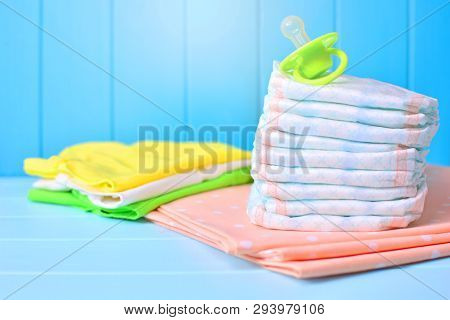 Baby Accessories Background. Pile Of Diapers, Clothes, Napkins And Dummy.
