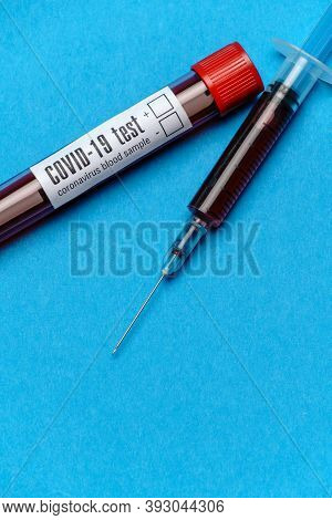 Syringe And Plastic Test Tube With Blood Sample Over Blue Background With Copyspace