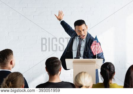 Excited Indian Agitator Gesturing While Talking To Voters In Conference Hall, Blurred Foreground