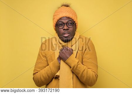 African American Mature Man In Yellow Scarf And Hat Freezing In Warm Clothing.