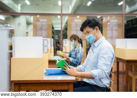 Two Asian University Students Wearing Face Mask And Sitting In Library Social Distance From Other 6 