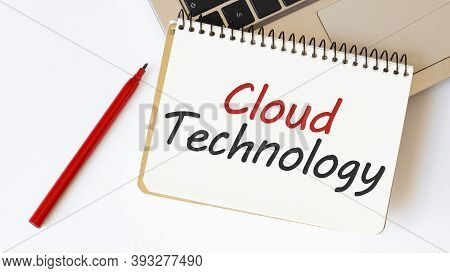 Laptop, Red Pen And Notepad With Text Cloud Technology In The White Background