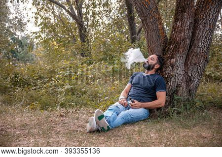 Handsome Vape Man Blows Up A Couple An Electronic Cigarette. Modern Ways Of Quitting Tobacco.