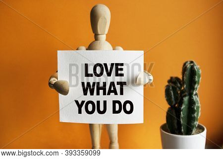 The Wooden Man Holds A White Sign With The Text Love What You Do In His Hands. The Content Of The Le