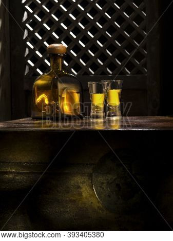 Close Up View Of Bottle Of Tequila Anejo And Glasses On Color Background