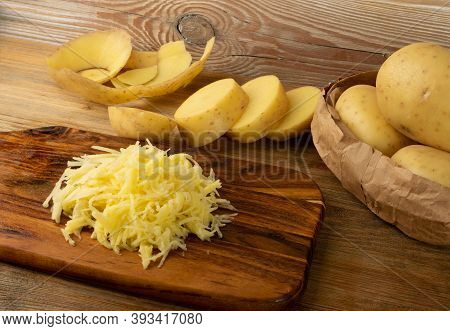Raw Grated Potato On Wooden Cutting Board Background
