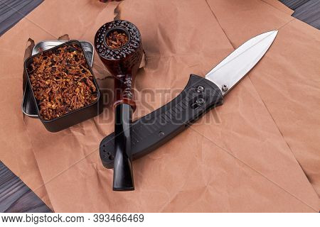 Composition Of Smoking Pipe With Tobacco And Knife. Countrymen Accessories On Beige Paper.