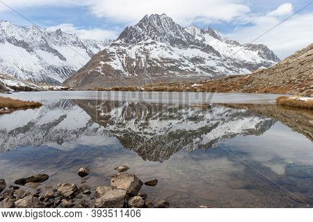 Winter Landscape Reflected In Calm Lake. Snow Covered Mountain Olmenhorn Reflected In Maerjelensee, 