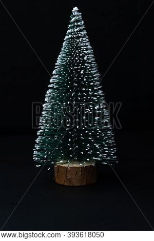 Artificial Fir Tree On A Black Background, Free Space For Text. Copy Space. Merry Christmas And Happ