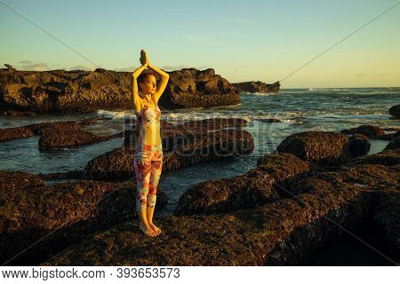 Caucasian Woman Standing On Big Stone During Low Tide. Yoga And Meditation At The Beach. Hands Raise