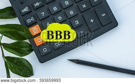 Bbb (better Business Bureau) - Word On A Yellow Note Sheet On A White Background With A Calculator, 