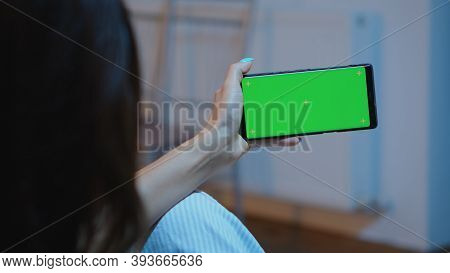 Lady Looking At Green Screen Smartphone While Relaxing At Home Sitting On Sofa. Woman Holding A Mobi