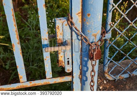 Old rusty gate locked by a padlock and chain