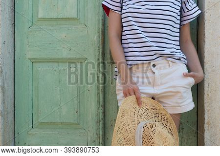 Fashinable Torso Portrait Of Woman Holding Sun Hat, Standing And Relaxing In Shade In Front Of Turqu