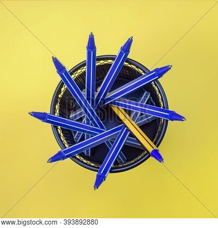 Blue Pens And One Yellow Pen In Metal Holder On Yellow Background. Top View. Selective Focus. Differ