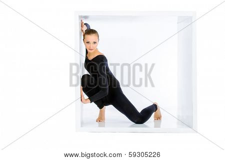 Modern bellet dancer posing with a cube at studio. Plastic body concept. Isolated over white.