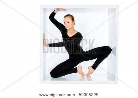 Modern bellet dancer posing with a cube at studio. Plastic body concept. Isolated over white.