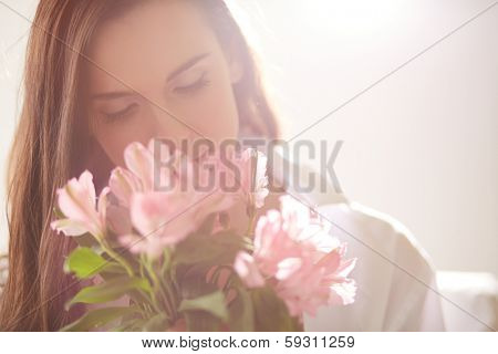 Portrait of lovely lady looking at flowers and smelling them