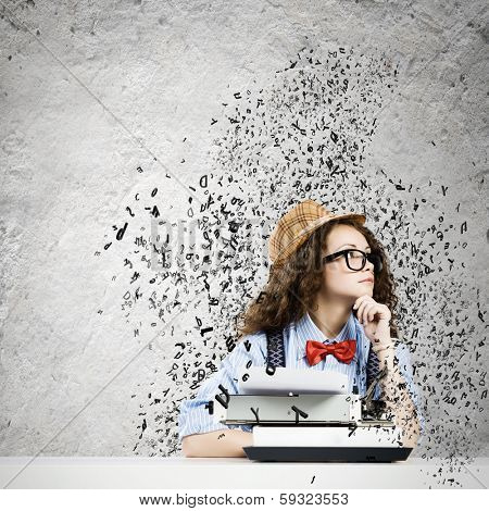 Young funny woman in glasses using typewriter