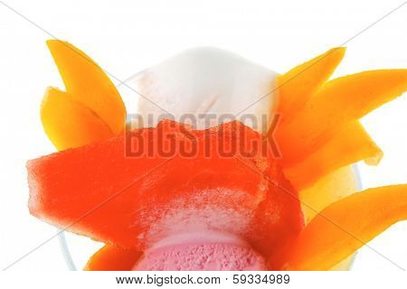 small transparent glass cup with ice cream and tropical fruits isolated on white background