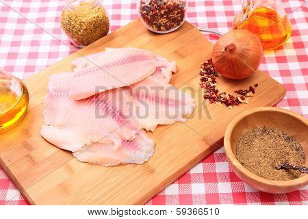Raw fish tilapia on cutting board and spices