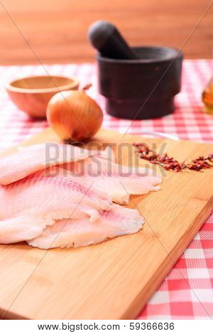 Raw fish tilapia on cutting board and spices