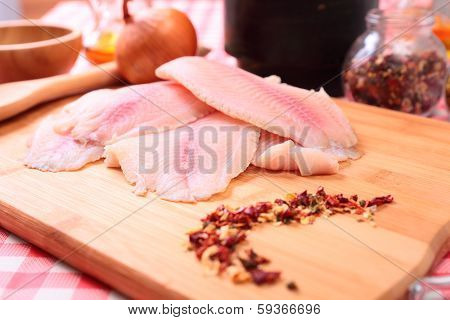 Raw fish tilapia on cutting board and spices