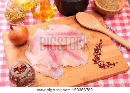 Raw fish tilapia on cutting board and spices