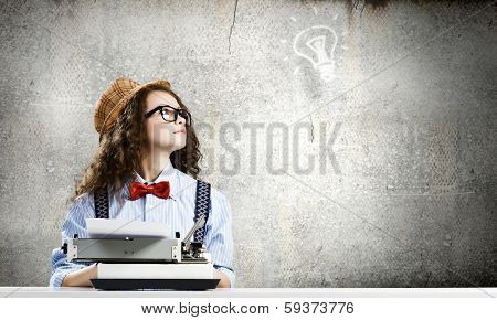 Young funny woman in glasses using typewriter
