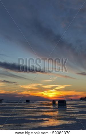 Ice fishing at sunset along the shores of rural Prince Edward Island.