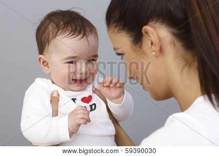 Elfish little boy smiling in mother's arms.