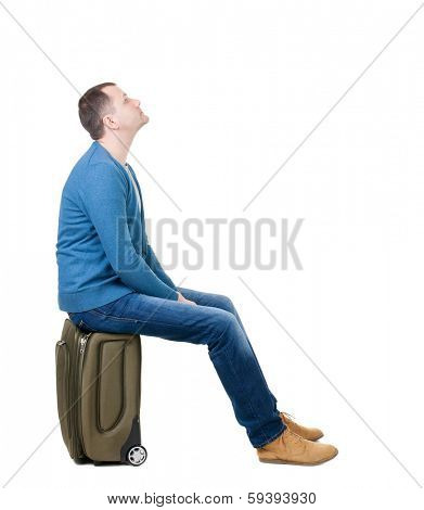 back view man sitting on suitcase. waiting at the station. backside view person.  Rear view people collection. Isolated over white background. guy with travel bag on wheels looking at something at top