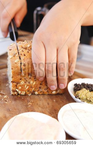 wooman cut the home made bread on wooden board near tapases outside cafe