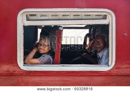 HIKKADUWA, SRI LANKA - MARCH 12, 2014: Commuters in train looking through window. Trains are very cheap and poorly maintained but it's the best option to witness a bit of everyday local life.