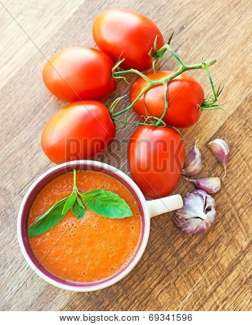 A bowl of tomato soup gaspacho with basil, tomatoes and garlic