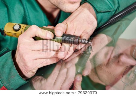 Automobile glazier repairman at windscreen repair of a car in auto service station garage
